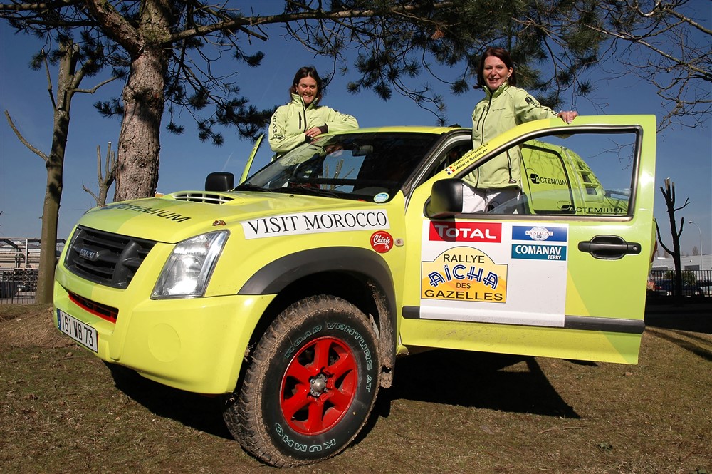 Deux femmes posant dans leur voiture de rallye de couleur jaune